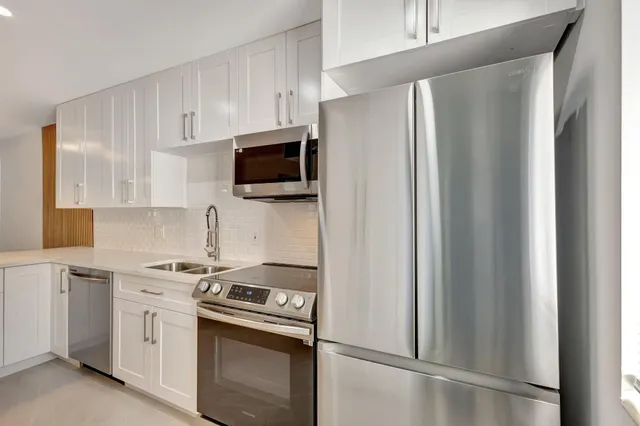 a kitchen with stainless steel appliances white cabinets and a refrigerator