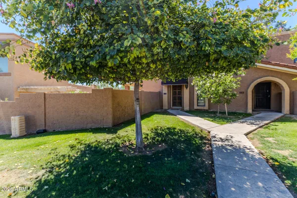 a view of a house with a yard plants and a large tree