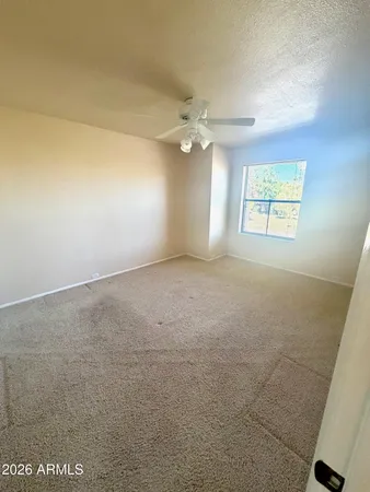 en empty room with windows and chandelier fan