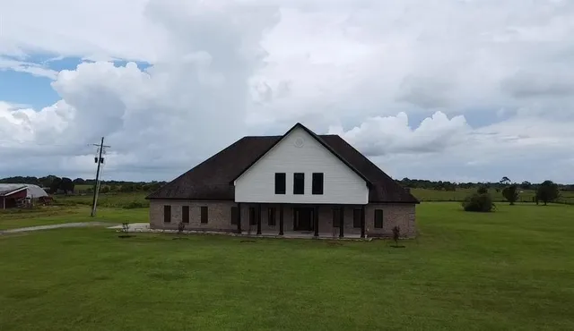 a view of a big house with a big yard and large trees