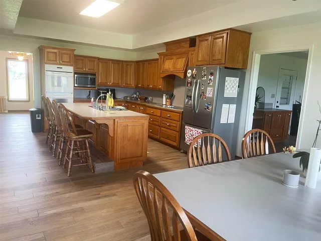 a kitchen with stainless steel appliances granite countertop a table chairs and a refrigerator