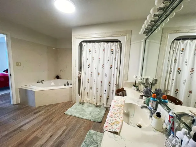 a spacious bathroom with a tub shower and sink