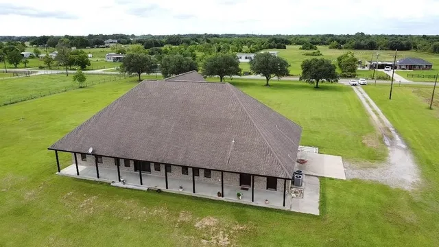an aerial view of a house with swimming pool and green yard