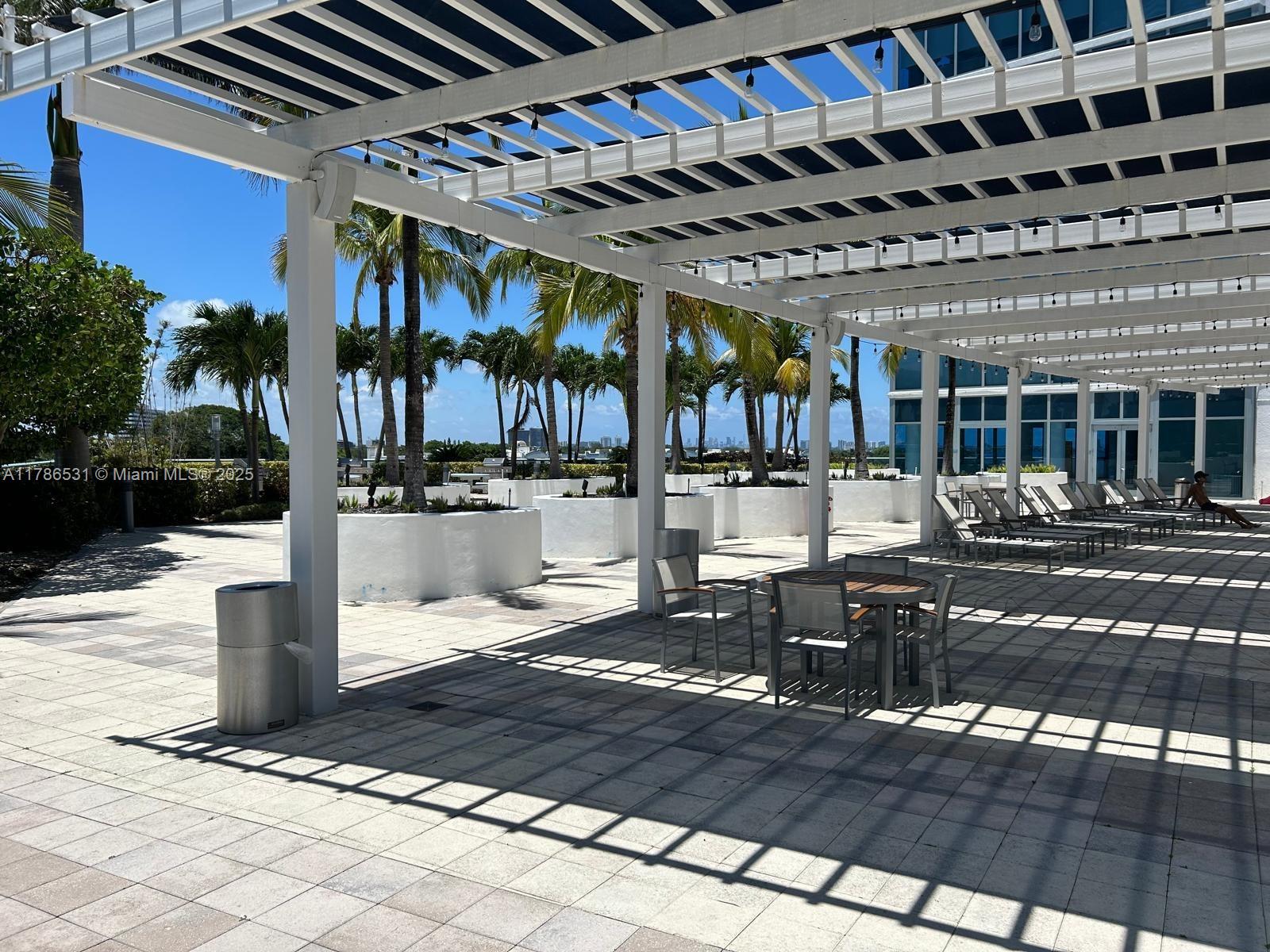 601 Northeast 36th Street, Unit 801 Miami, FL 33137 - Photo 17 of 24 a view of a patio with table and chairs with wooden floor and plants