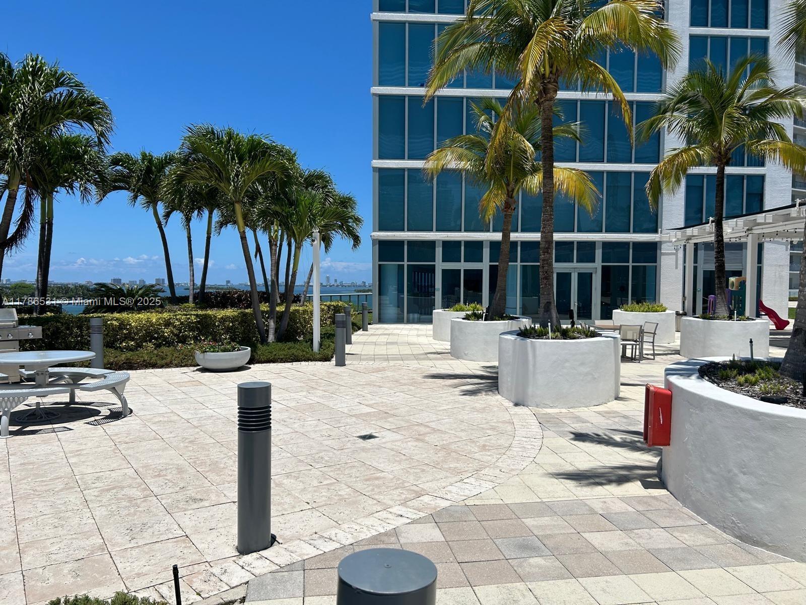 601 Northeast 36th Street, Unit 801 Miami, FL 33137 - Photo 18 of 24 a view of a swimming pool with a lounge chair and palm trees