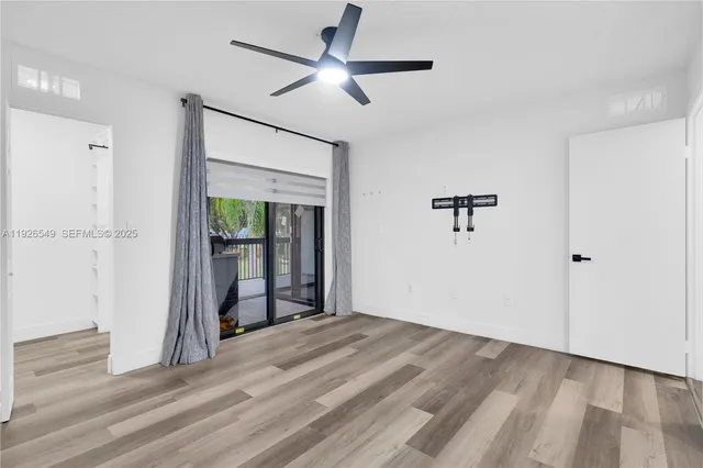 a view of empty room with wooden floor and fan