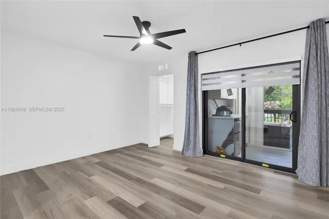 a view of empty room with wooden floor and fan