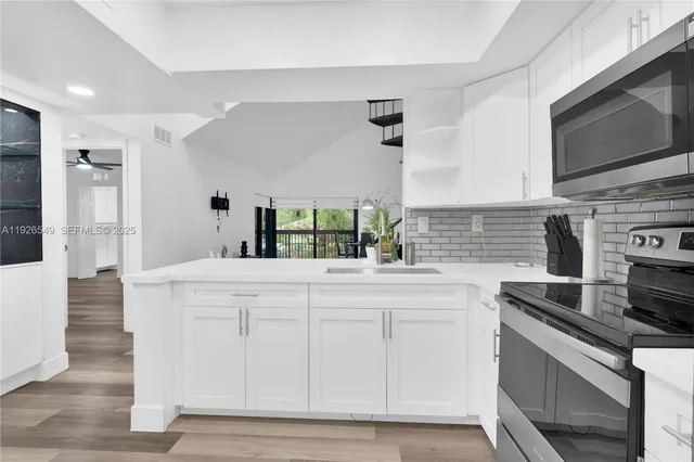 a kitchen with stainless steel appliances white cabinets and a stove top oven