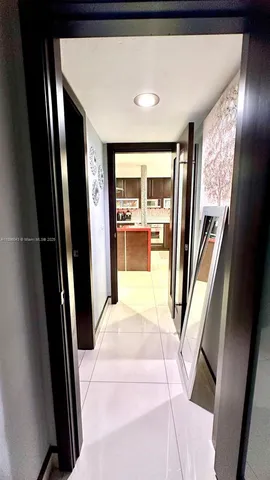 a view of a hallway with wooden floor and a living room