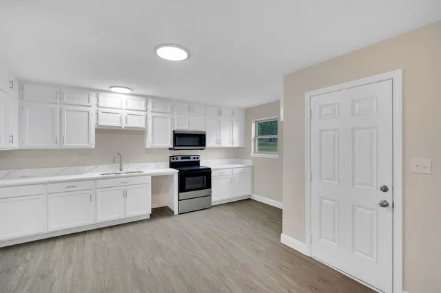 a kitchen with granite countertop white cabinets and appliances