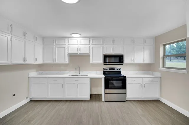 a kitchen with stainless steel appliances a stove a sink and white cabinets