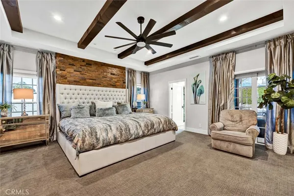 a bedroom with a large bed couch and windows