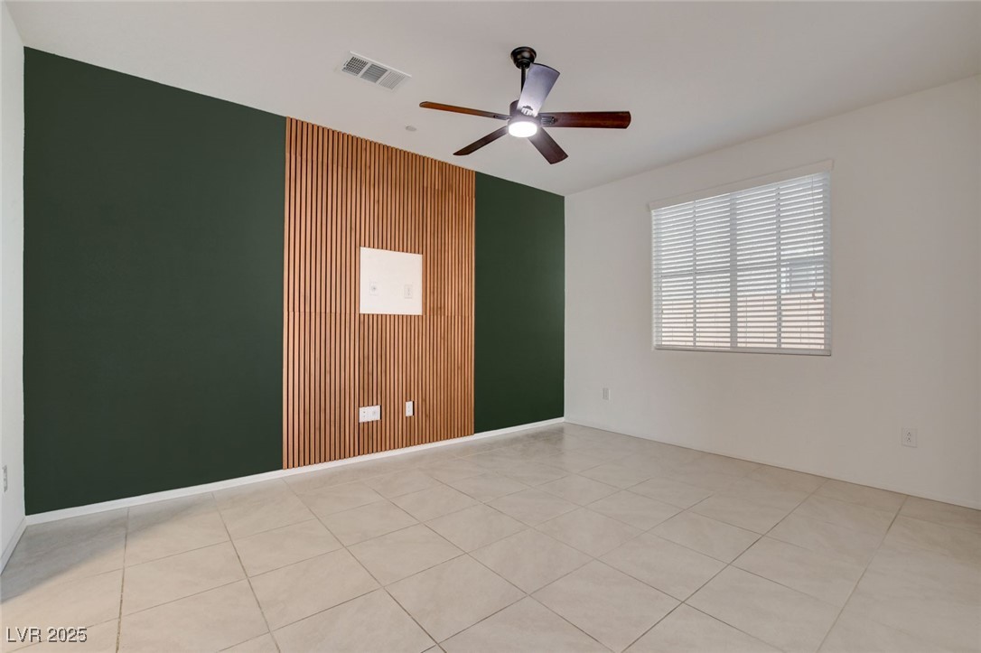 1360 Cerulean Avenue Henderson, NV 89002 - Photo 10 of 62 Empty room featuring light tile patterned floors, a ceiling fan, and wood walls
