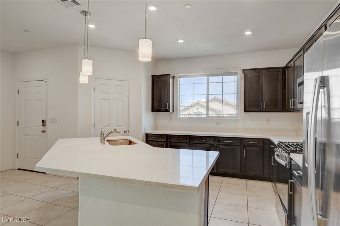 1360 Cerulean Avenue Henderson, NV 89002 - Photo 16 of 62 Kitchen featuring appliances with stainless steel finishes, hanging light fixtures, recessed lighting, dark brown cabinets, and an island with sink
