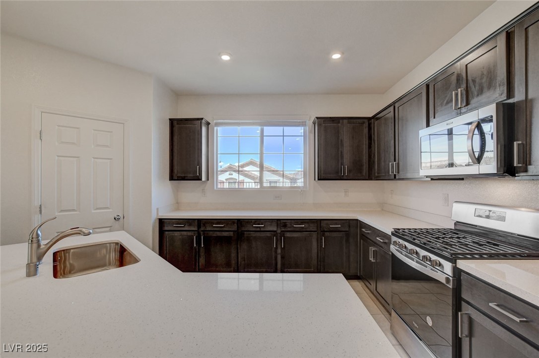 1360 Cerulean Avenue Henderson, NV 89002 - Photo 21 of 62 Kitchen with appliances with stainless steel finishes, dark brown cabinets, light stone countertops, and recessed lighting