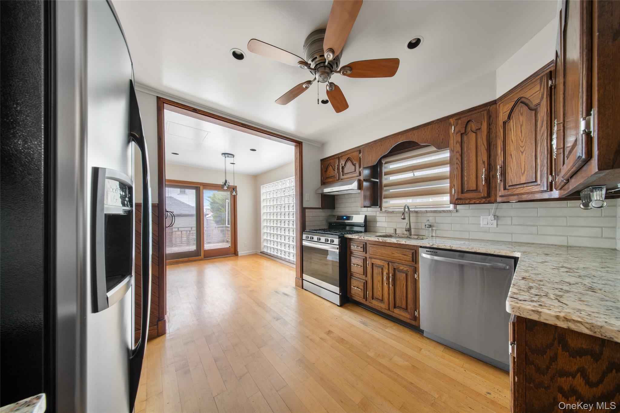 47-69 195th Street Queens, NY 11358 - Photo 10 of 12 a kitchen with stainless steel appliances granite countertop hardwood floor sink stove dining table and chairs