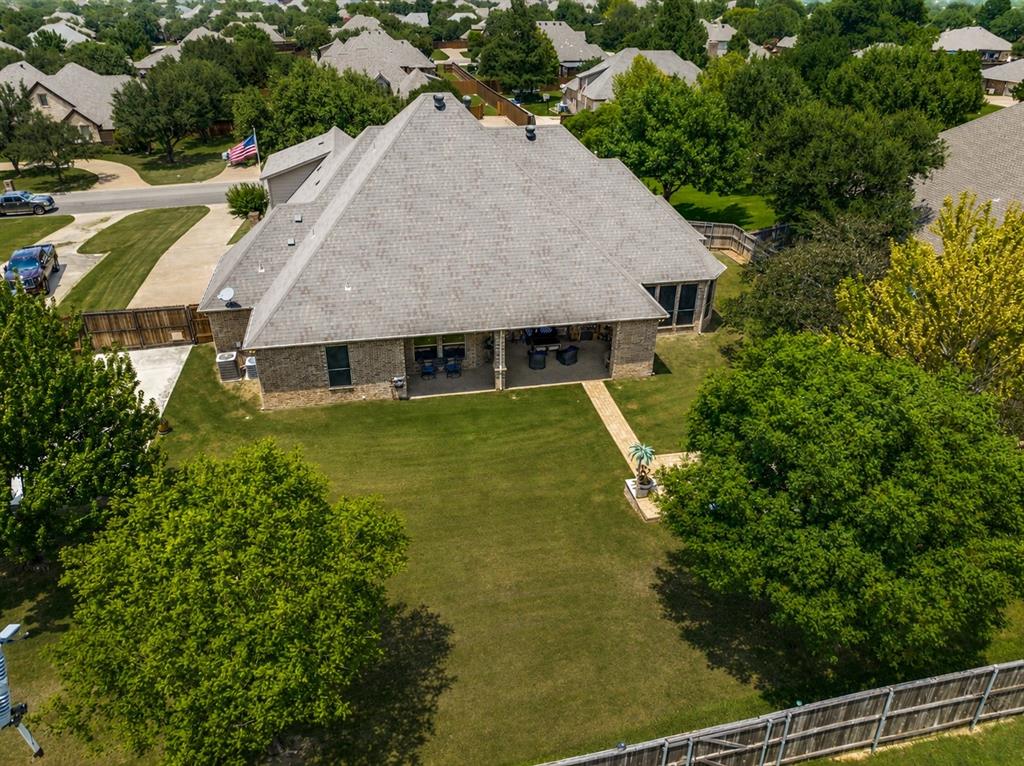 229 Arbor Lane Haslet, TX 76052 - Photo 31 of 34 Brick exterior residence with an expansive rear lawn, mature landscaping, and a covered back patio