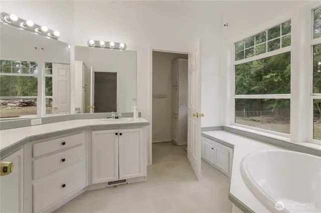 a spacious bathroom with a tub sink and mirror