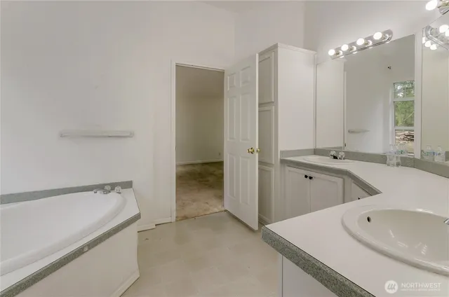 a bathroom with a tub sink and mirror