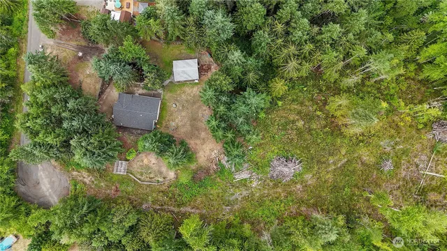 an aerial view of residential house with outdoor space and trees all around