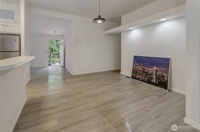 a view of an empty room with a window and wooden floor