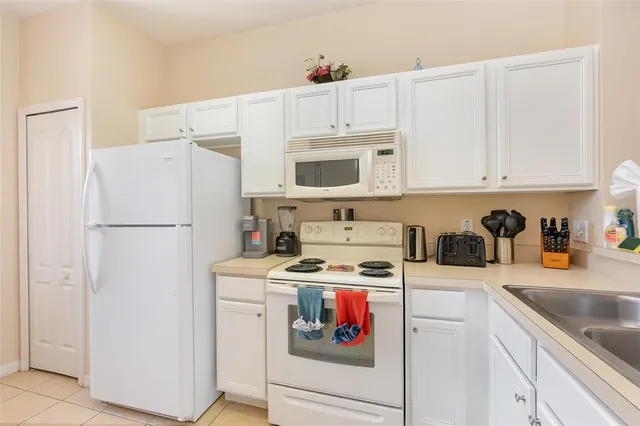 a kitchen with stainless steel appliances granite countertop a refrigerator sink stove and white cabinets