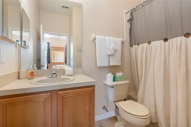 a bathroom with a sink a toilet a mirror and shower curtain