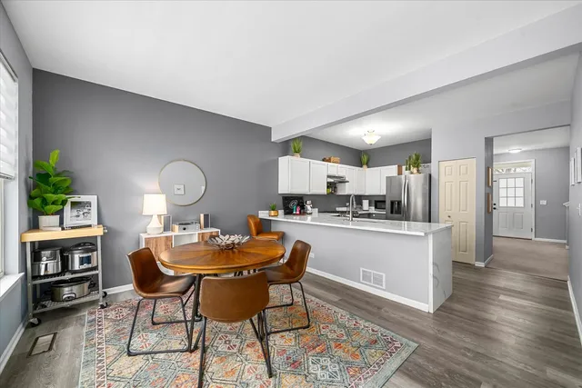 a dining room with wooden floor and a kitchen