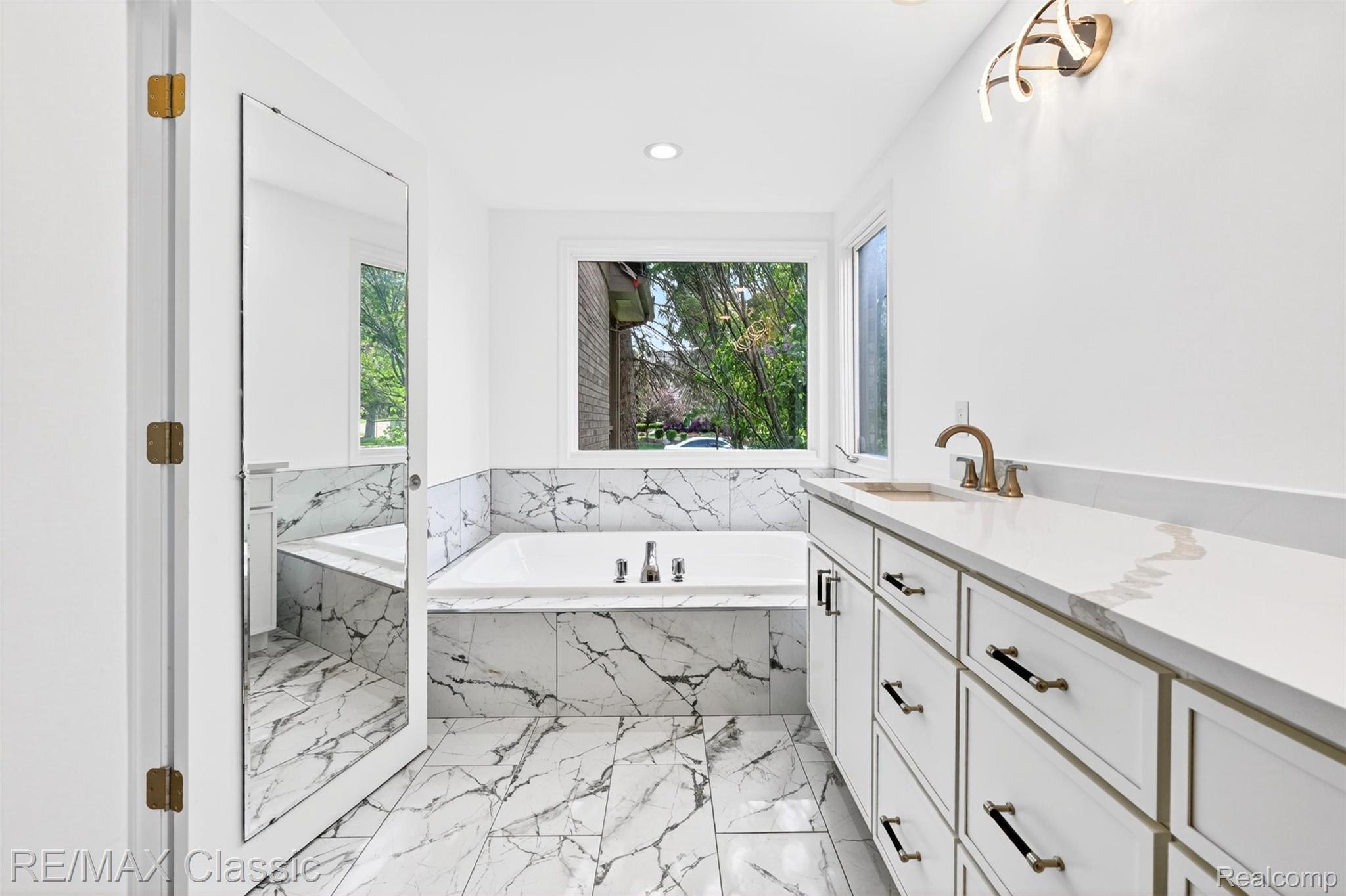 30779 Country Ridge Circle Farmington, MI 48331 - Photo 14 of 46 White bathroom featuring a built-in tub with marble-look tile surround and flooring