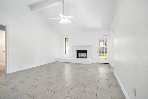 an empty room with windows and fireplace