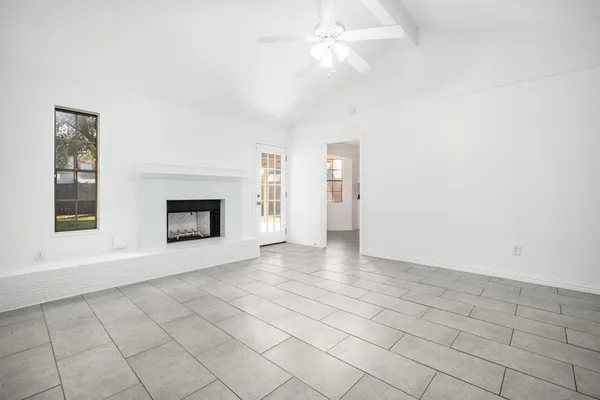 an empty room with windows and fireplace