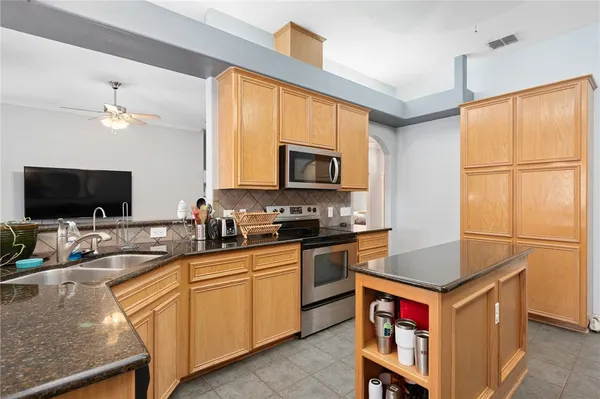 a kitchen with stainless steel appliances granite countertop a stove a sink and a microwave