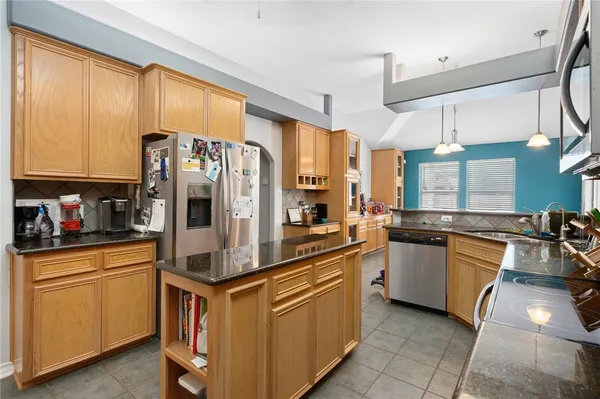 a kitchen with stainless steel appliances granite countertop a stove a sink and a refrigerator