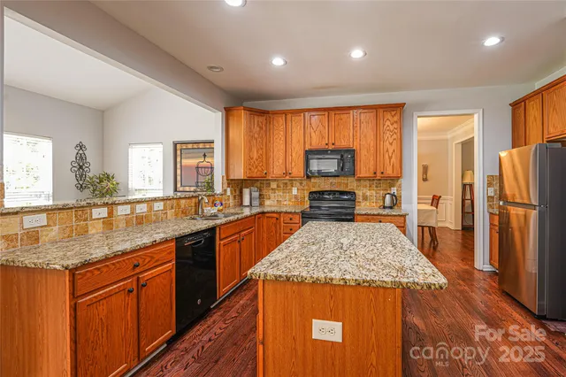 a kitchen with stainless steel appliances granite countertop sink stove refrigerator and cabinets