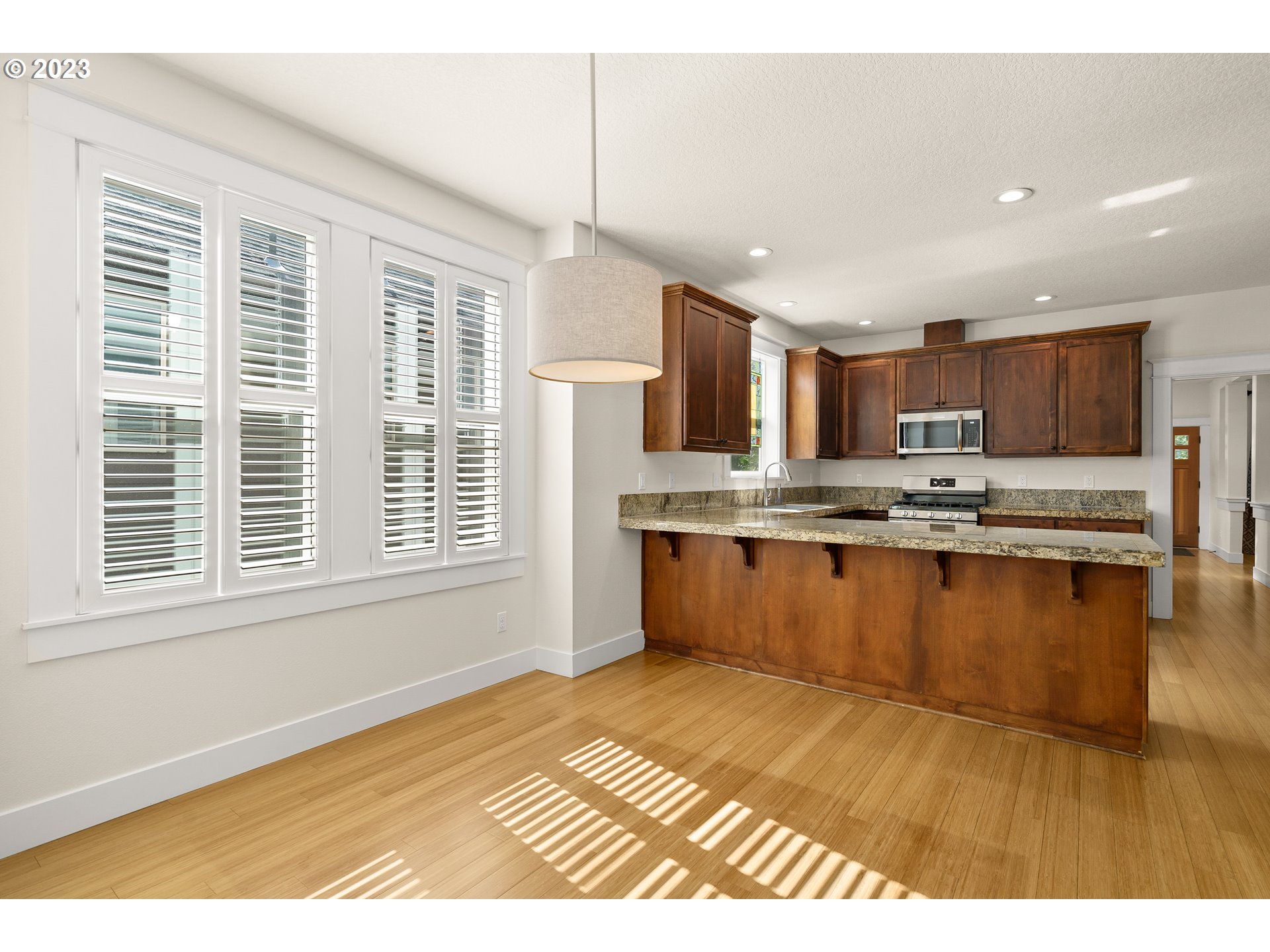 3917 Southwest Stephenson Street Portland, OR 97219 - Photo 19 of 34 a open kitchen with granite countertop a stove top oven a sink dishwasher a dining table and chairs with wooden floor