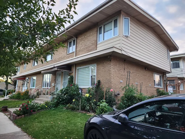 a view of a house with a yard plants and large tree