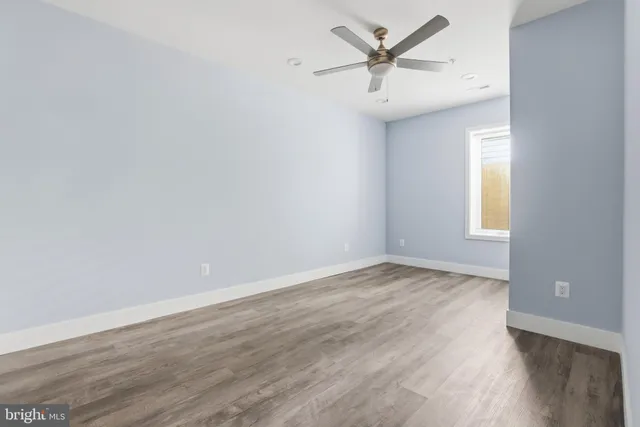 an empty room with wooden floor and a ceiling fan