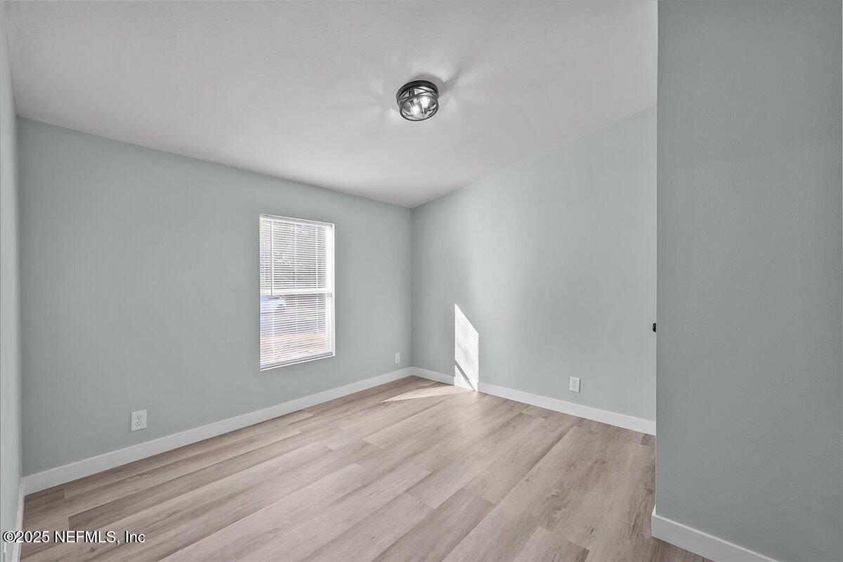 316 Sheila Avenue Interlachen, FL 32148 - Photo 16 of 22 a view of an empty room with wooden floor and a window