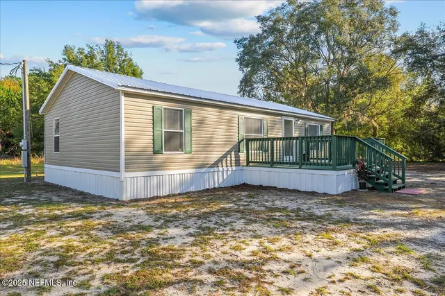a view of a house with a small yard and large tree