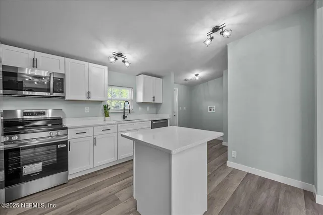 a kitchen with kitchen island a sink stainless steel appliances and cabinets
