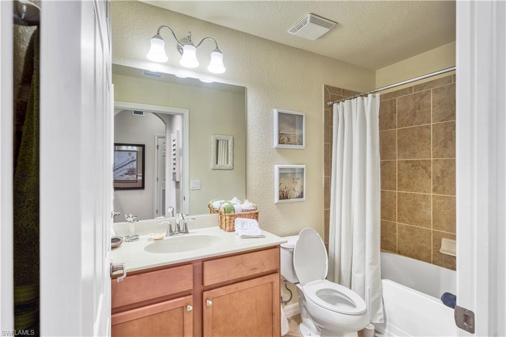 9715 Acqua Court, Unit 136 Naples, FL 34113 - Photo 20 of 24 a bathroom with a sink a toilet a mirror a vanity and shower