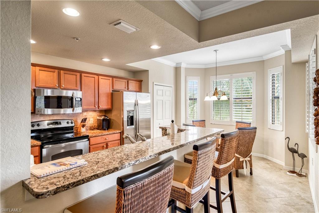 9715 Acqua Court, Unit 136 Naples, FL 34113 - Photo 6 of 24 a large kitchen with kitchen island granite countertop a large counter top space appliances and cabinets