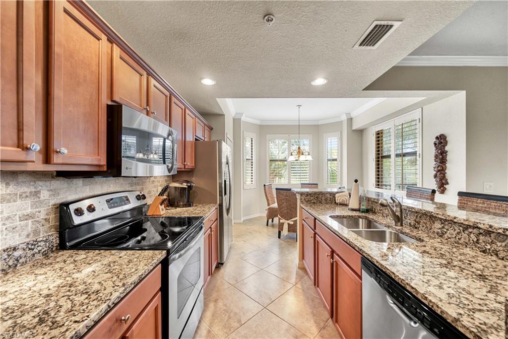 9715 Acqua Court, Unit 136 Naples, FL 34113 - Photo 7 of 24 a kitchen with stainless steel appliances granite countertop a sink stove and refrigerator