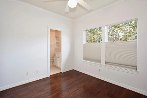 an empty room with wooden floor cabinet and windows