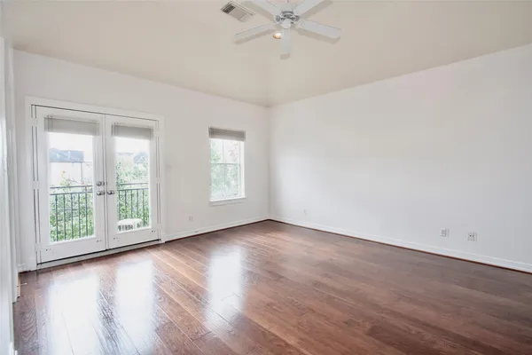 an empty room with wooden floor chandelier fan and windows