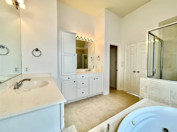 a spacious bathroom with a tub sink and mirror