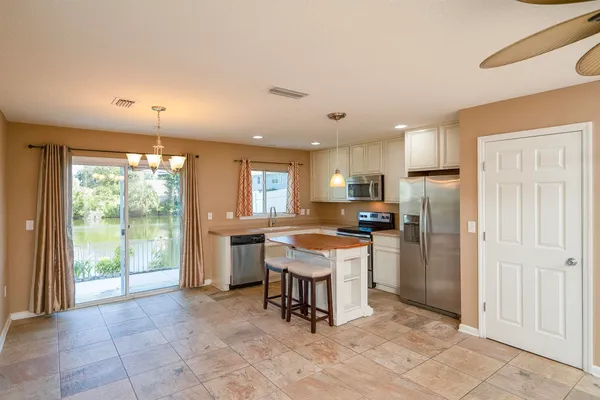 a kitchen with stainless steel appliances granite countertop a refrigerator a sink a stove a dining table and chairs