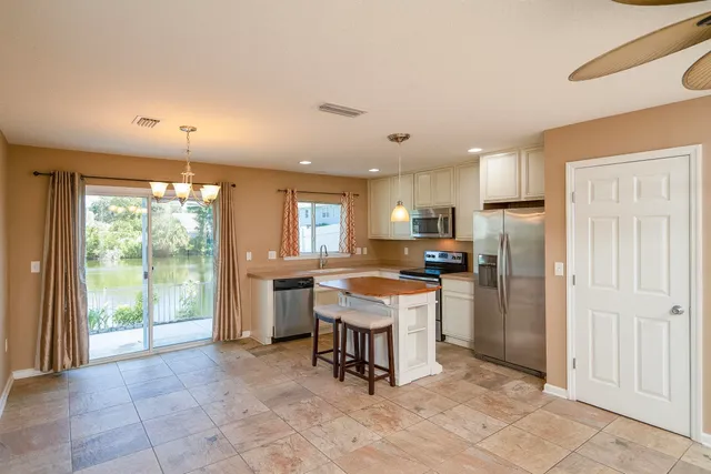 a kitchen with stainless steel appliances granite countertop a refrigerator a sink a stove a dining table and chairs