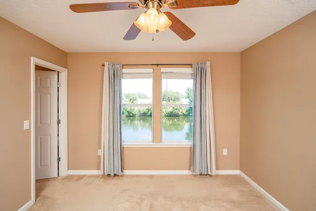 a view of a big room with windows and chandelier fan