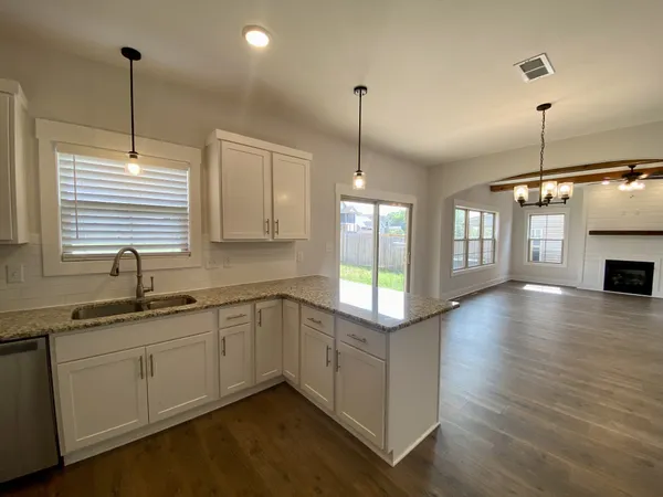 a kitchen with stainless steel appliances granite countertop a sink a window and wooden floor